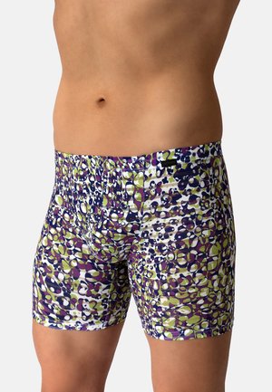 Männlicher Torso mit eng anliegenden Boxershorts mit einem mehrfarbigen abstrakten Muster in Lila, Grün, Schwarz und Weiß auf einem einfarbigen Hintergrund.