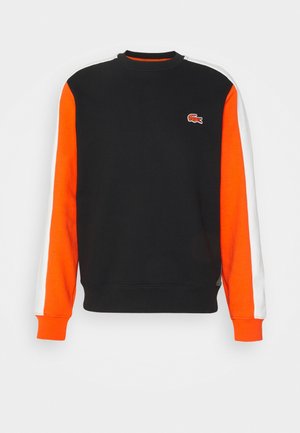 Zwart crewneck sweatshirt met oranje en witte strepen op de mouwen en een klein oranje krokodillenlogo op de borst.