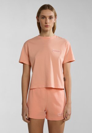 Perzikkleurig katoenen t-shirt met korte mouwen en een boxy pasvorm, gecombineerd met bijpassende shorts. Bevat een klein geborduurd logo op beide items.