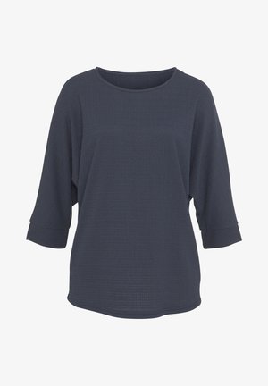 Tamsiai mėlynas, tekstūruotas ilgomis rankovėmis viršus su plačia iškirpte ir trijų ketvirčių rankovėmis. Laisvas siluetas, su suktomis rankovėmis ir tiesiu apvadu.