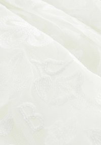 Biely vyšívaný textil so vzorom kvetov a jemnou textúrou, ktorý zobrazuje zložitú výšivku a priesvitnú kvalitu.