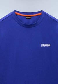 Livlig blå bomulds T-shirt med rund halsudskæring, der har et orange accent ved kraven og et lille hvidt logo på brystet.