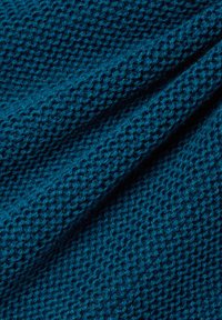 Dunkelblau gestrickter Stoff mit einer strukturierten, gemusterten Oberfläche. Die Fasern sind dick und verflochten, was ein weiches, taktiles Erscheinungsbild erzeugt.