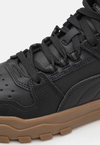 Baskets en cuir noir avec un dessus texturé, dotées d'une semelle rembourrée, d'accents en caoutchouc et de lacets plats. Boîte à orteils perforée pour la ventilation.