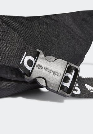 Sangle en tissu noir avec une boucle à libération latérale en plastique embossée du logo Adidas et du symbole trèfle.