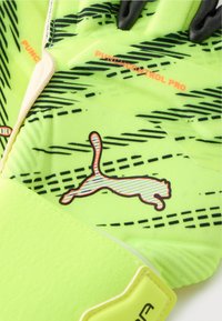 Ποδοσφαιρικά γάντια τερματοφύλακα σε νέον κίτρινο με μαύρες γραμμές ανάδειξης. Διαθέτουν λαστιχένια λαβή και ανάγλυφο λογότυπο Puma. Υφή για βελτιωμένο έλεγχο.