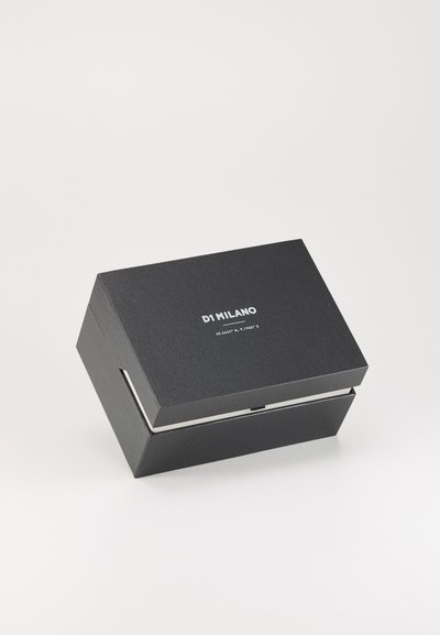 Boîte noire rectangulaire avec une finition texturée, dotée de quincaillerie en argent et du texte "DI MILANO" en blanc sur la surface supérieure.
