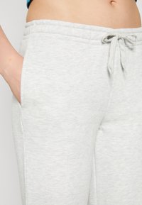 Lys grå joggebukser laget av mykt materiale, med elastisk midje, snor og sidelommer. Glatt, teksturert stoff.