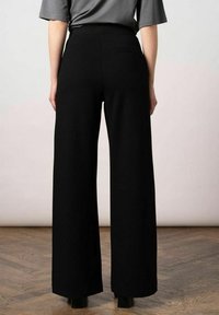 Wijde zwarte broek gemaakt van zachte stof, met een hoge taille en strakke lijnen. Minimalistisch ontwerp zonder zichtbare versieringen.