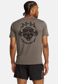 T-shirt grigio con una grande grafica nera di una tigre ruggente circondata da rose e fili spinati. Maniche corte, materiale cotone.