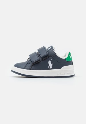 Baskets enfant bleu marine avec deux bandes Velcro, semelle blanche, logo joueur de polo blanc et languette de talon verte avec texte blanc.