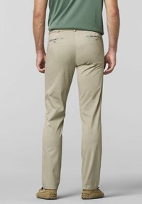 Beige chino's met een slim fit en een subtiele textuur. Voorzien van achterzakken met unieke, patroonrand. Gecombineerd met tan schoenen, wat comfort uitstraalt.