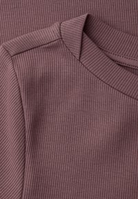 Zbliżenie na wrzosową dzianinę prążkowaną, pokazujące szew na ramieniu oraz szczegóły przeszyć przy okrągłym dekolcie.