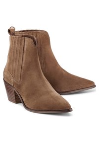 Botines de ante marrón con punta puntiaguda, tacones apilados y detalles de costura vertical en los laterales. Textura lisa en general.