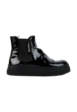 Bottine Chelsea en cuir noir brillant avec panneau latéral élastique et semelle en caoutchouc épaisse, comportant le logo Prada sur l’élastique latéral.