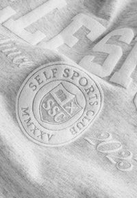 Halli spordipusa materjal tekstuuriga tähistustega, featuring "SELF SPORTS CLUB" logo, aasta "2023" ja reljeefne ümmargune embleem.