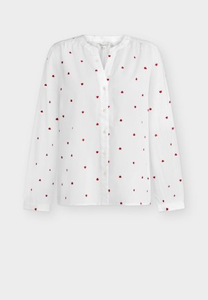 Biała bluzka z długim rękawem w małe czerwone serduszka, z okrągłym dekoltem i zapinana na guziki z przodu.