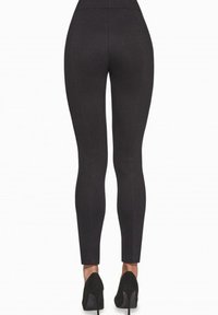 Czarne legginsy z wysokim stanem o dopasowanym fasonie, z widocznym przeszyciem i gładką fakturą, w połączeniu z czarnymi szpilkami.
