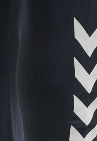 Close-up of black fabric with a vertical row of white chevron arrows pointing down along the right side.