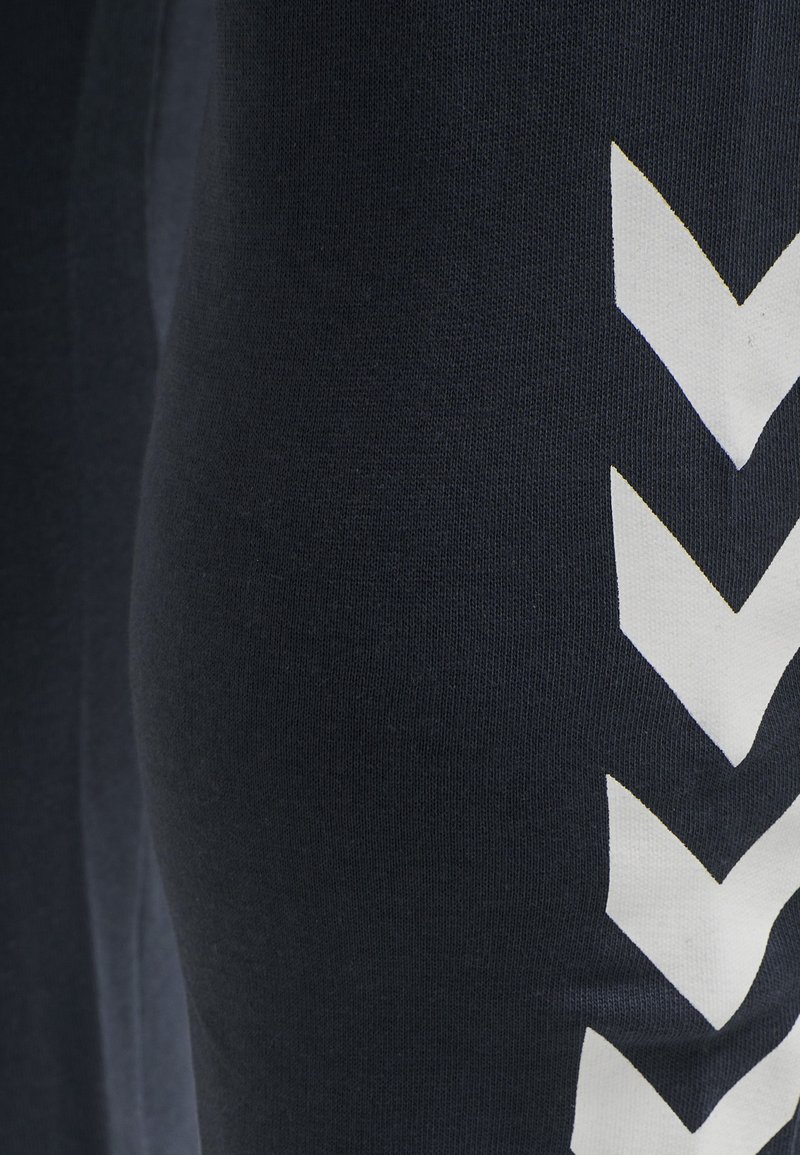 Leggings azul marino hechos de tejido suave, con un patrón de zigzag blanco a lo largo de un lado para un acento gráfico. Textura lisa, diseño ajustado.