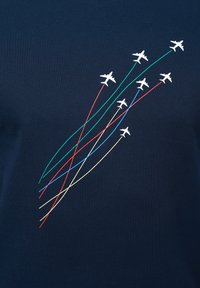 Camiseta de algodón azul marino con aviones blancos y líneas de colores (verde, rojo, azul, amarillo) que representan rutas de vuelo en un ángulo ascendente.