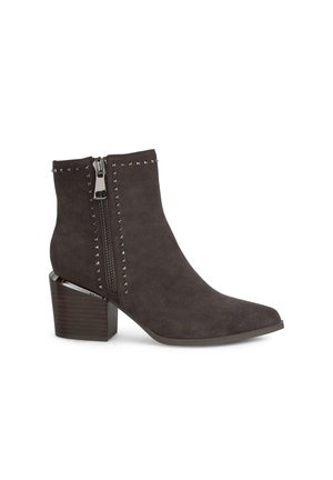 Botín de ante gris oscuro que presenta una puntera puntiaguda, cremallera de hardware plateado, acentos con tachuelas y un tacón grueso de estilo madera.