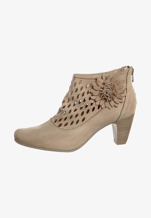 Botas de tobillo beige con un diseño recortado, un acento de flor texturizada y un tacón bloque. Material suave con un cierre de cremallera en la parte posterior.