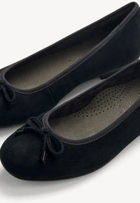 Black suede ballet flats with rounded toes, small bows on the front, and cushioned, perforated insoles for comfort.