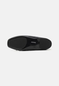 Black patent leather shoe sole with vertical ridges and a smooth surface. Features embossed logo and rounded toe design.