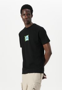 Black cotton t-shirt featuring a blue floral embroidery on the chest. Classic crew neckline and short sleeves. Smooth texture, regular fit.