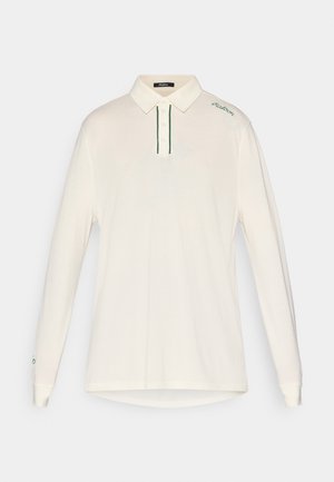 Langermet kremfarget polo-skjorte med spiss krage, tre-knaps placket, grønne detaljer i sømmen og brodert logo på skulderen.