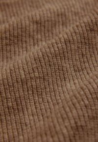 Strukturiertes braunes Gewebe mit vertikalem Rippenmuster, weicher Oberfläche und leichtem Glanz, geeignet für verschiedene Textilanwendungen.