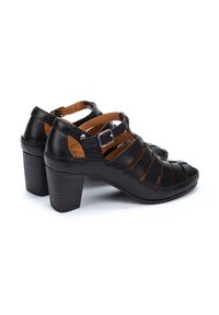 Schwarze Leder-High-Heelsandalen mit einem Riemendesign, offener Zehenpartie und einem klobigen strukturierten Absatz. Mit verstellbarem Knöchelriemen und silbernem Beschlag.