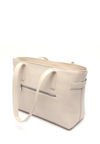 Vaaleanbeige nahkainen laukku, jossa on kaksi kantokahvaa, avara yläosa ja takana vetoketjullinen ulkotasku. Sujuva pinta ja suorakulmainen muoto.