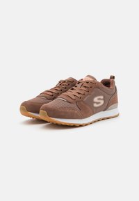 Brown athletic shoes with a mesh and suede upper, rubber outsole, and a logo on the side. Features laces and a cushioned collar.