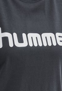 Šedé bavlněné tričko s velkým bílým logem "humm" na hrudi. Výstřih je kulatý a látka vypadá hladce.