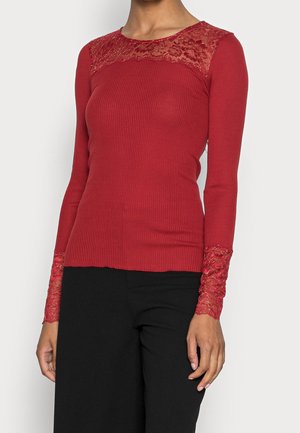 Top de manga larga rojo acanalado con detalles de encaje en los hombros y puños. La tela es suave y tiene una silueta ajustada.