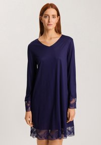 Abito blu navy realizzato in tessuto morbido, con maniche lunghe e delicata rifinitura in pizzo attorno alle maniche e all'orlo. Design a V.