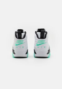 Sneakers bianche alte con accenti neri e verde menta, dotate di un tallone testurizzato, logo Nike prominente e design con imbottitura ad aria.