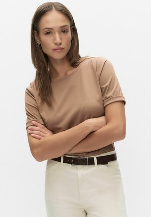 Bruine T-shirt met korte mouwen, gecombineerd met crèmekleurige broek en een donkerbruine riem. Glad, aansluitend materiaal met een ronde halslijn en opgerolde mouwen.