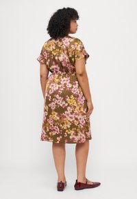 Brown floral dress featuring short sleeves, cinched waist, and a knee-length skirt. Flowers in pink and yellow against a darker background.