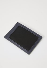 Cardholder de culoare bleumarin, cu un fereastră din plasă texturată neagră și cusături contrastante. Design subțire, de formă rectangulară, ușor și funcțional.