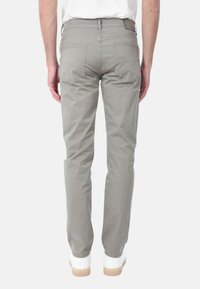 Chinos grigi con una design a gamba dritta, dotati di due tasche posteriori, una texture liscia e indossati con sneakers bianche su uno sfondo semplice.