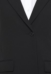 Zwarte blazer met rever met inkeping, eenknopsluiting en twee voorzakken. Gemaakt van gladde stof met een getailleerde pasvorm.