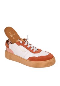 Scarpa caratterizzata da una combinazione di pelle bianca e suede arancione, con una suola in gomma testurizzata, punta rotonda e lacci bianchi. Logo in bronzo sul lato.