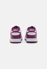 Les baskets Nike présentent un dessus en cuir violet avec des accents blancs. Le design comprend un col rembourré et une semelle en caoutchouc texturé.