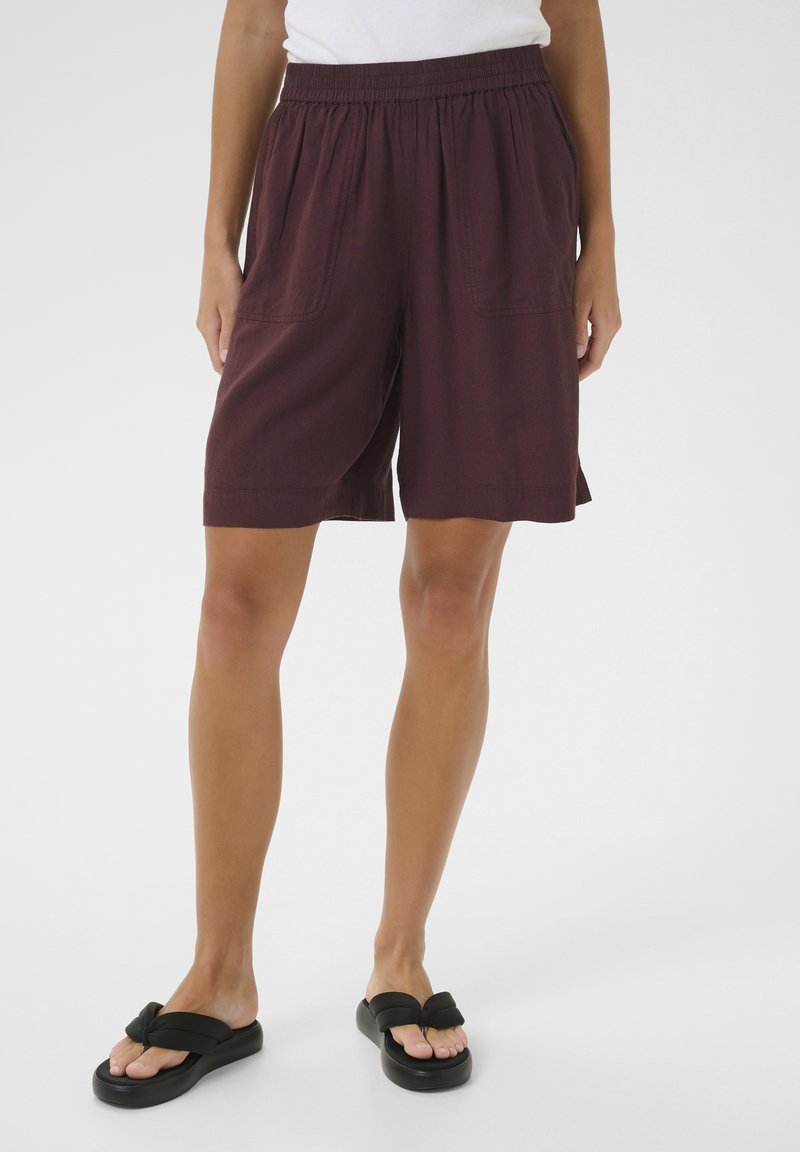 Shorts bordeaux avec une taille élastique, deux poches latérales et une coupe ample. Assortis à des sandales noires à enfiler.