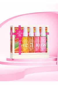 Set di quattro flaconi spray in una scatola. I flaconi contengono liquidi trasparenti, giallo, arancione e rosa; tappi bianchi. La scatola presenta uno sfondo testurizzato e colorato.
