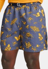 Marinblå shorts med ett detaljerat mönster av gula insekter, elastisk midja med spänne och sidofickor i mesh.