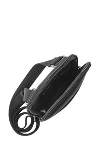 Čierna látková crossbody taška s textúrovaným povrchom. Obsahuje dvojitý zip pre otváranie a nastaviteľný popruh. Kompaktný a funkčný dizajn.
